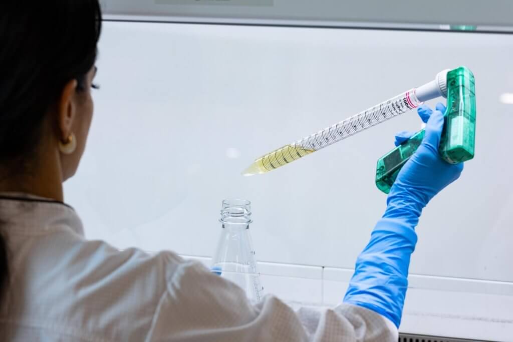 Scientist pipetting liquids in sterile laboratory in Zurich for recombinant antibody production